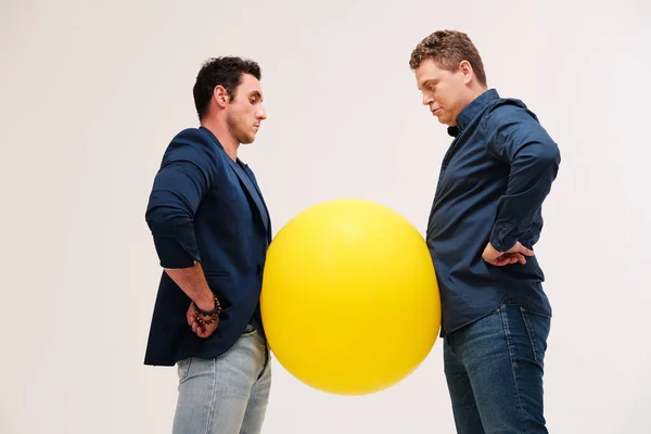 Retrato Estúdio Dois Homens Posando Com Grande Bola Amarela Contra — Fotografia de Stock