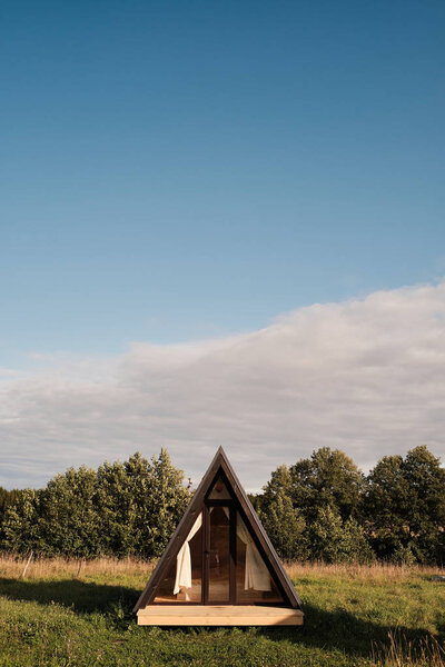 Деревянный треугольный сарай со стеклянной дверью в сельской местности луг
