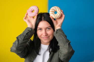 Mavi ve sarı arka planda donut kulağı yapan neşeli kız