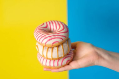 Mavi ve sarı arka planda tatlı çörek yığınını tutan kadın.