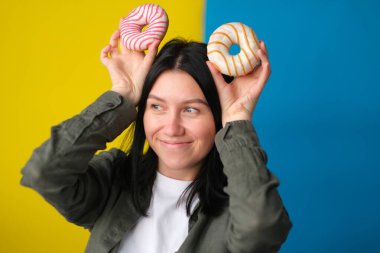 Mavi ve sarı arka planda donut kulağı yapan neşeli kız