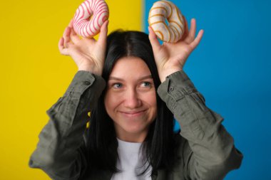 Mavi ve sarı arka planda donut kulağı yapan neşeli kız