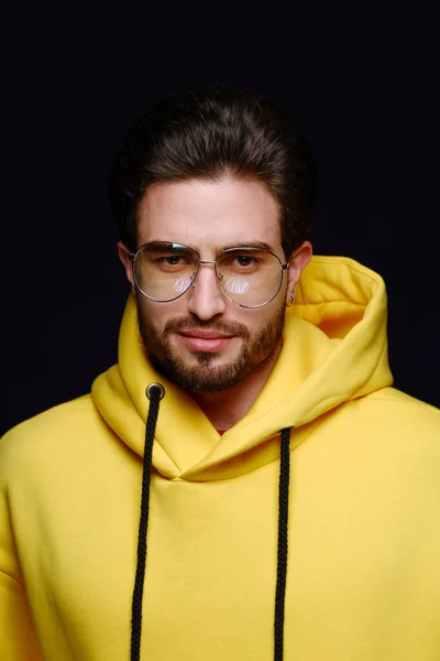 Un jeune homme de 25-30 ans en lunettes et un sweat-shirt jaune pose émotionnellement sur un fond violet. — Photo