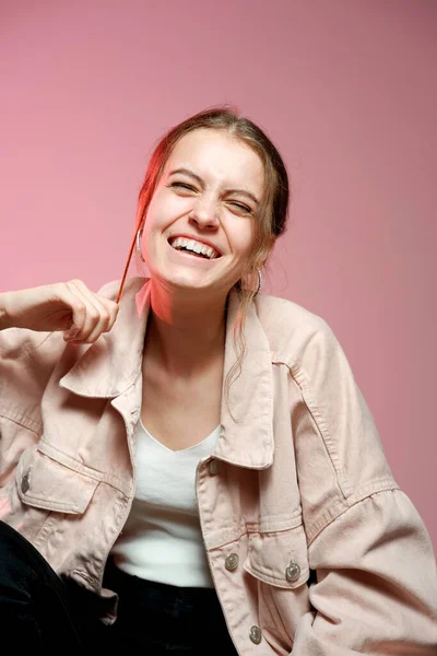 Una chica en un denim rosa muestra diferentes emociones y posa sobre un fondo rosa . — Foto de Stock