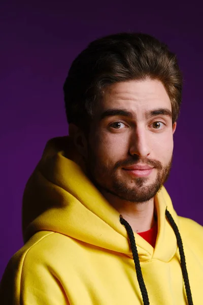 Un giovane di 25-30 anni in felpa gialla posa emotivamente su uno sfondo viola. — Foto Stock
