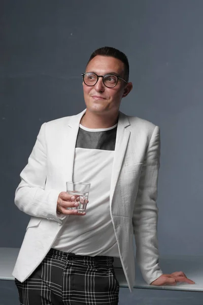 30-35 yaşlarında beyaz ceketli, gözlüklü ve kısa saçlı genç bir adam elinde suyla camdan bir bez tutuyor.. — Stok fotoğraf