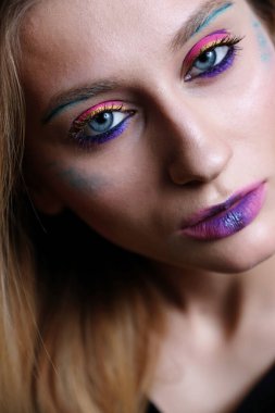 20-25 yaşlarında, parlak makyajlı ve mavi gözlü güzel bir kızın yakın plan portresi..