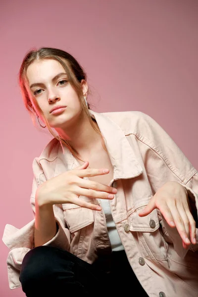 Una chica en un denim rosa muestra diferentes emociones y posa sobre un fondo rosa . — Foto de Stock