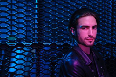 Çok renkli neon ışıklı arka planda izole edilmiş güzel beyaz adam portresi.. 