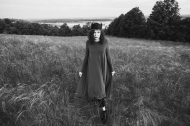 25-30 yaşlarında, kıvırcık saçlı, elbisesi ve güzel arka planda tüyleri olan siyah-beyaz bir kadının portresi..