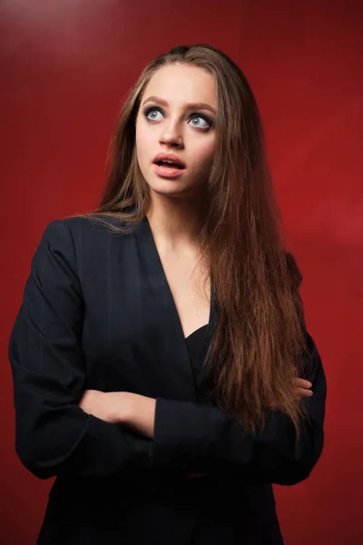 Retrato de una joven hermosa niña de 20-25 años con diferentes emociones en una chaqueta sobre un fondo rojo — Foto de Stock