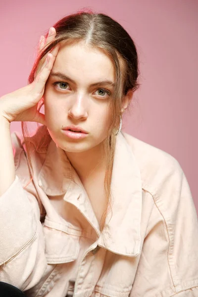 Una chica en un denim rosa muestra diferentes emociones y posa sobre un fondo rosa . — Foto de Stock