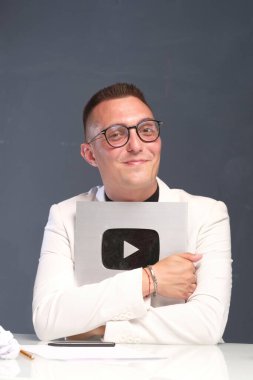 Kısa saçlı, gözlüklü, açık tişörtlü, elinde oyun sembolü olan 30-35 yaşlarında bir adam..