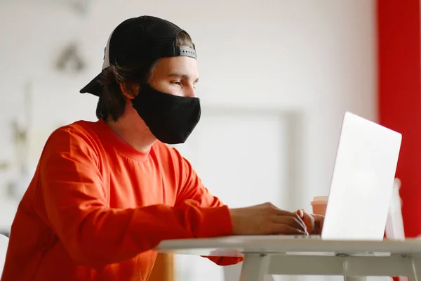 El hombre se sienta solo en una mesa en el espacio abierto, bebiendo café y trabajando en su computadora portátil. Concepto independiente —  Fotos de Stock