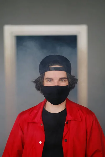 Retrato de un joven de 25-30 años con máscara protectora negra, gorra y chaqueta roja . Fotos De Stock