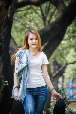 Tayland Asyalı kadın bir T-shirt ve jeans giymiş. Genel parkta mutluyuz