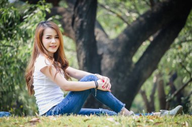 Tayland Asyalı kadın bir T-shirt ve jeans giymiş. Genel parkta mutluyuz