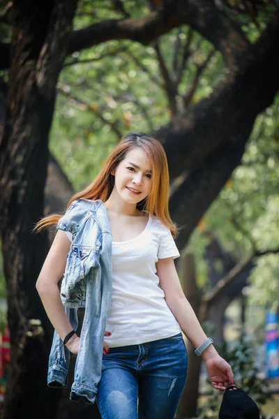 Tayland Asyalı kadın bir T-shirt ve jeans giymiş. Genel parkta mutluyuz