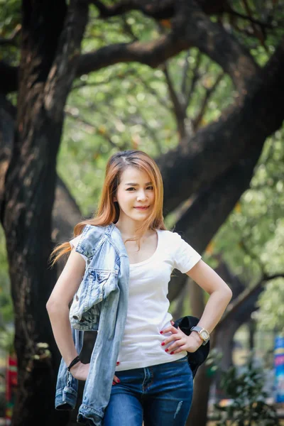 Tayland Asyalı kadın bir T-shirt ve jeans giymiş. Genel parkta mutluyuz