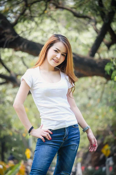 Tayland Asyalı kadın bir T-shirt ve jeans giymiş. Genel parkta mutluyuz