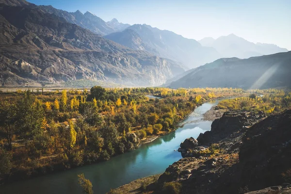 Güz Gakuch renkli orman içinden nehir akışı göstermek ve karakurum aralığındaki dağlarla çevrili. Ghizer, Gilgit-Baltistan, Pakistan.