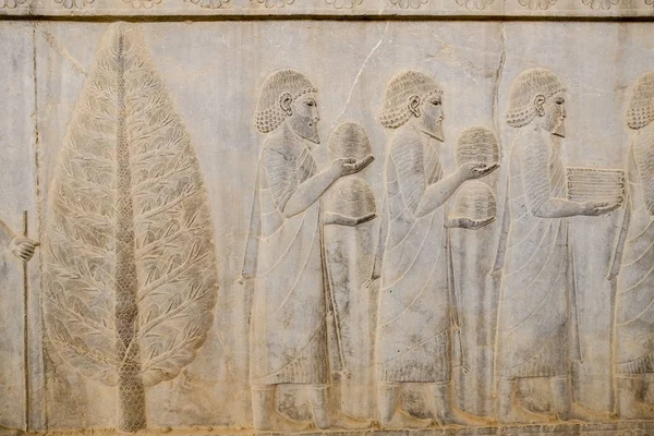 A bas-relief of ancient Greeks men were bearing gifts at Apadana, East Stairs, southern part of Persepolis. Shiraz, Iran.
