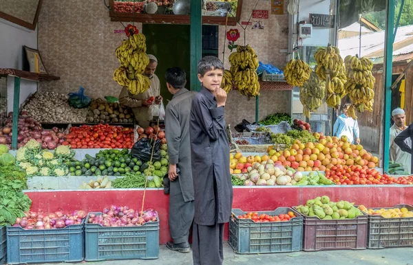 Un hombre vendiendo frutas y verduras a un cliente en una tienda de comestibles . — Foto de Stock
