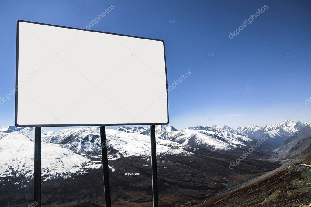 An outdoor white blank billboard with a view of clear blue sky and snow capped mountain range in the background. Karakoram highway, Barbusar Pass. Gilgit Baltistan, Pakistan.