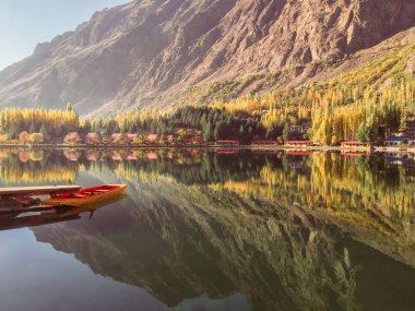 Sonbahar huzur içinde alt Kachura göl. Durgun su ve bitki örtüsü dağ içinde belgili tanımlık geçmiş ile bir görünüm dayalı tekne. Skardu, Gilgit Baltistan, Pakistan.