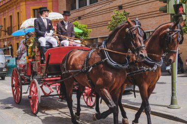Sevilla, Ispanya. 4 Mayıs 2017: Sevilla Nisan Fuarı 'nda veya Feria de Abril de Sevilla 'da bir at arabasıyla seyahat eden geleneksel kostümlü erkek ve kadınlar. Endülüs.