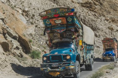 Gilgit Baltistan, Pakistan. Ekim 11, 2015: Pakistan dekore edilmiş kamyonlar asfalt yol üzerinde seyahat, dağ boyunca Karakoram karayolu üzerinden taşıma malları.