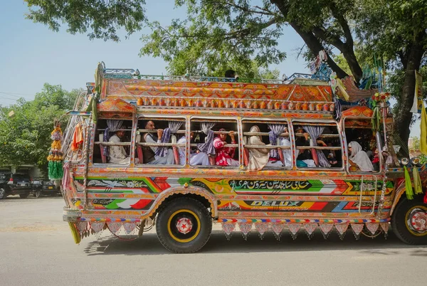 Pencap, Pakistan. Ekim 4, 2015 : Pakistanlı erkek ve kadın yolcular ile bir sokakta güzel renkli yerel dekore otobüs park.