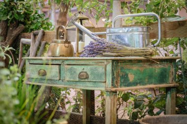 Bir su ısıtıcısı, sulama olabilir ve eski tarz ahşap yeşil masa üzerinde lavanta çiçekleri demet. Yazlık açık bahçe rustik ülke tarzı dekorasyon. Seçici odaklama.
