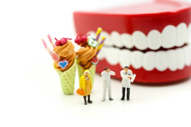 Minyatür insanlar: diş hekimi ve diş hasta ve tatlı dondurma ile sağlık tıbbi kavramı önünde sağlık ekibi.