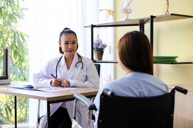 Güzel kadın doktor omurga bir kemik üzerinde diz eklem yerleşimini hastayla işaret ediyor.