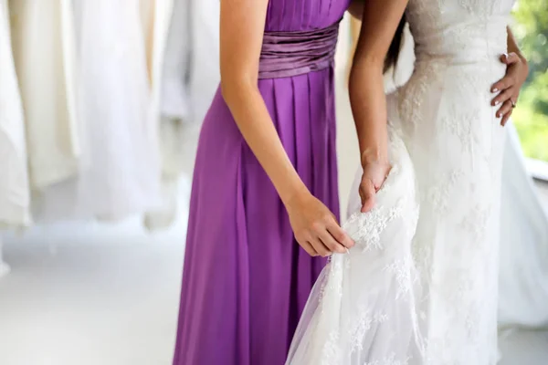 美しい花嫁彼女の親友で彼女の結婚式の日の結婚式のドレス店と店員を選択する服を着るを手伝った — ストック写真