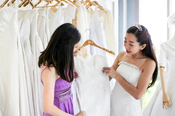 美しい花嫁彼女の親友で彼女の結婚式の日の結婚式のドレス店と店員を選択する服を着るを手伝った ストック画像