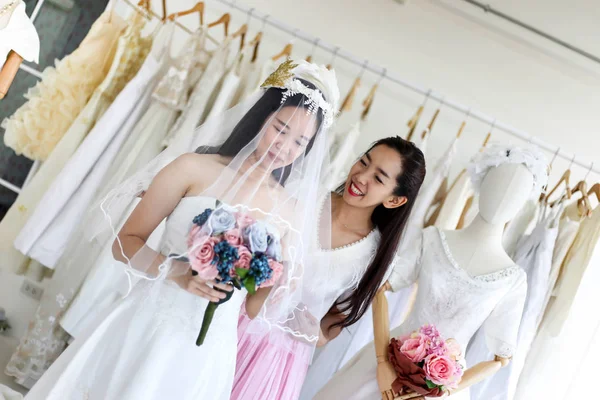 美しい花嫁彼女の親友で彼女の結婚式の日の結婚式のドレス店と店員を選択する服を着るを手伝った ストック写真