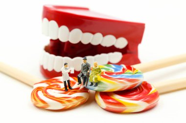 Minyatür insanlar: bir hastanın diş inceleyerek hasta ve tatlı lolipop, sağlık tıbbi kavramı ile diş hekimi.