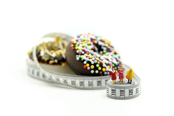 Miniature people : Fat woman and friend with Donut tying by measuring tape,dietary for slim shape concept.