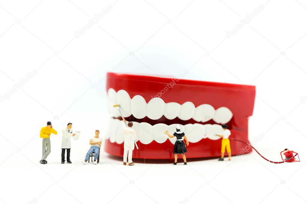 Miniature people : clean tooth or dental model with Dentist examining a patient's teeth ,using for concept of Dentist's Day.