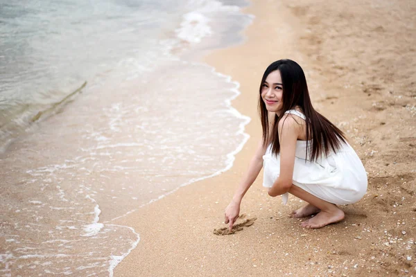 아름다운 아시아 소녀가 모래 위에서 글을 쓰고 있어요 — 스톡 사진