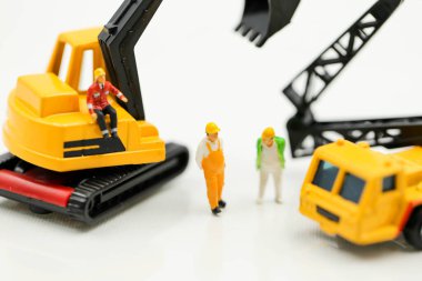 Minyatür insanlar: Kazıcı traktörlü bir inşaat sahasında çalışan işçi ve mühendis grubu