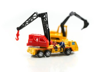 Minyatür insanlar: Kazıcı traktörlü bir inşaat sahasında çalışan işçi ve mühendis grubu