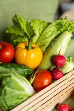 Ahşap kutuda meyve ve sebzeler yeşil arka planda..