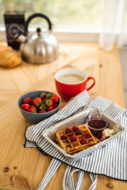 Kahvaltıda Belçika waffle 'ı. Taze böğürtlen ve böğürtlen reçelli waffle. Masada bir fincan kahve ve çaydanlık var. Karavanda kahvaltı. Yüksek kalite fotoğraf
