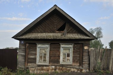 Evin eski ahşap duvarındaki pencereleri kapatmış. Oyma eski pencereyi süslüyor. Eski kütüklerden evin duvarları yakın çekim. Eski bina
