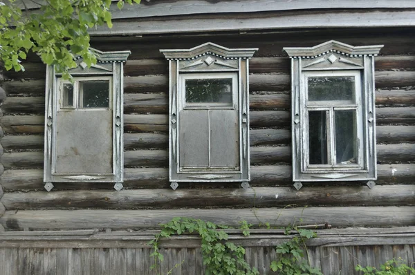 Bordade upp fönster på den gamla trä väggen i huset. Carving pryder det gamla fönstret. Väggarna i huset från de gamla loggarna närbild. Gamla byggnaden — Stockfoto