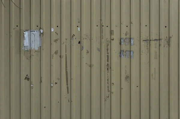 Vida ile sarı saclar, oluklu bir çit. Metal çit dokusuna