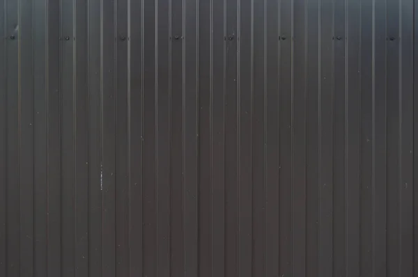 Siyah metal çit. Oluklu levha veya profilli levha. Ön. Metalik arka plan. Çizgili dokulu arka plan. Kahverengi Demir Yol. Çivit rengi